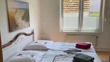Una camera da letto con un letto, una finestra con persiane, un termosifone e un quadro appeso al muro.