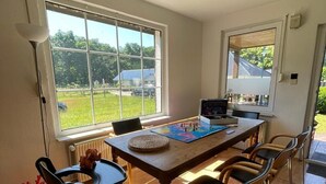 Ein Essbereich mit Holztisch, Stühlen, einem Globus und einem Fenster mit Blick auf Grünflächen.