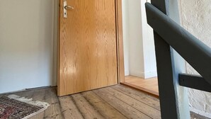 Ein Zimmer mit Holztür, Holzboden und einer schwarzen Metalltreppe.