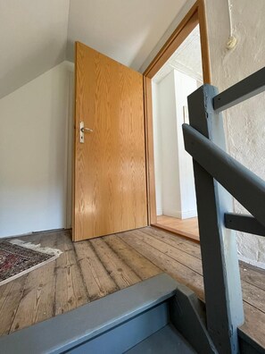 A room with a wooden door, a wooden floor, and a black metal staircase.