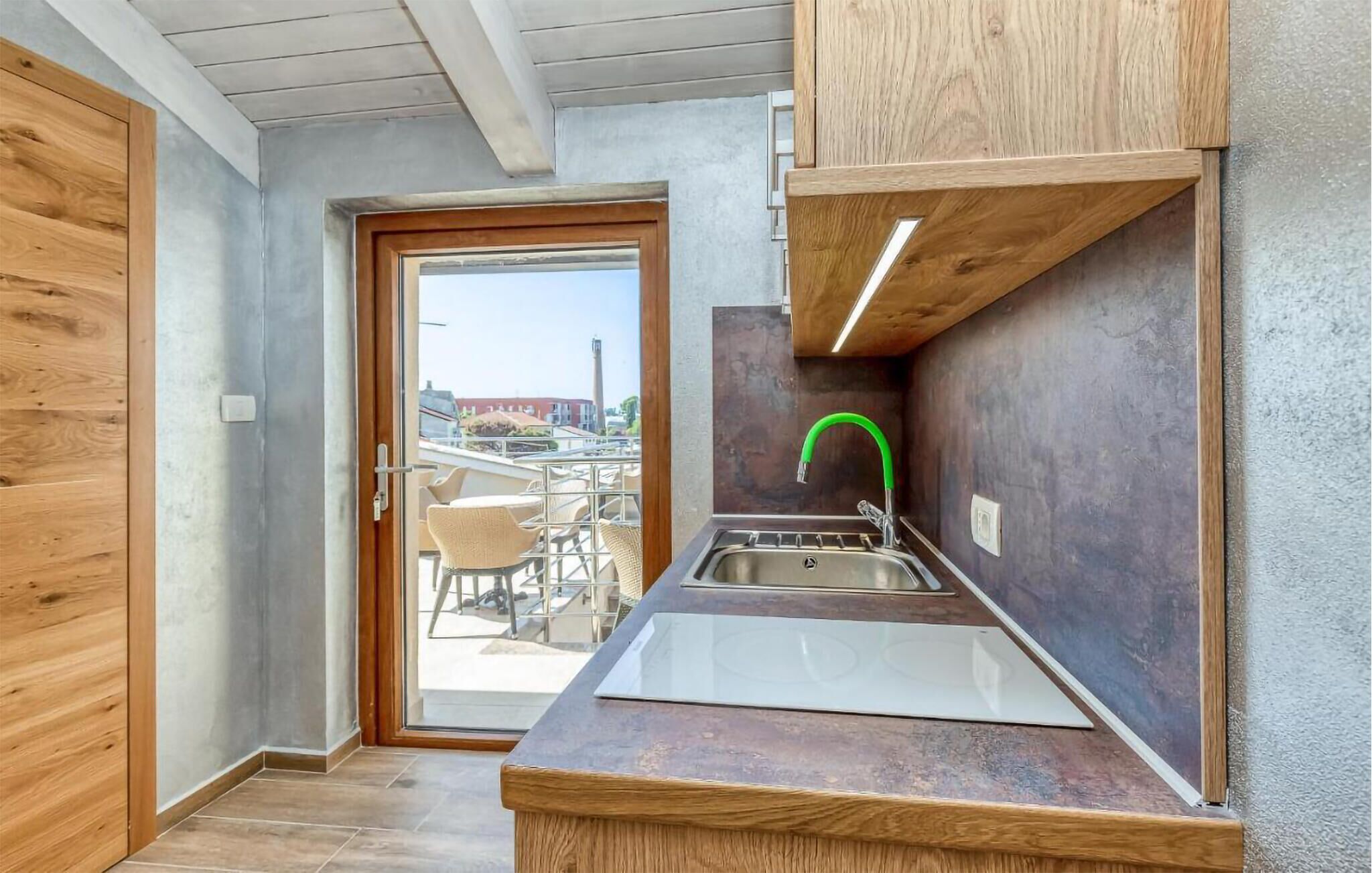 Una cocina compacta con lavamanos, armarios de madera y vistas a través de la puerta.