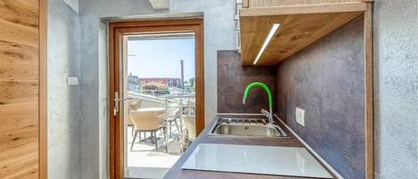 Una cocina compacta con lavamanos, armarios de madera y vistas a través de la puerta.