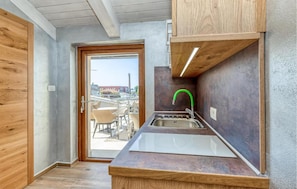 A compact kitchen with a sink, wooden cabinets, and a view through the door. - Beach front apartment in Umag with house sea view (Umag)