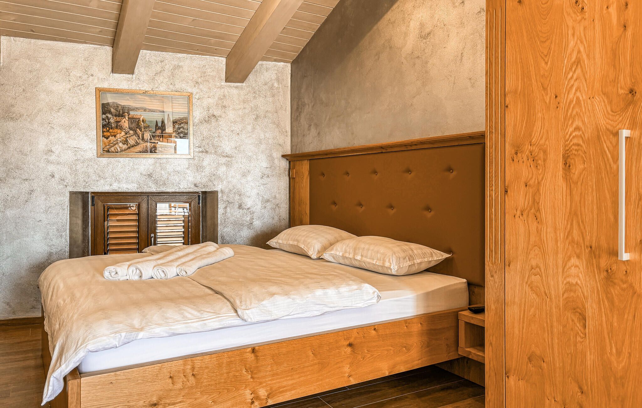Quarto com cama de madeira, cabeceira, guarda-roupa de madeira e um quadro emoldurado na parede.