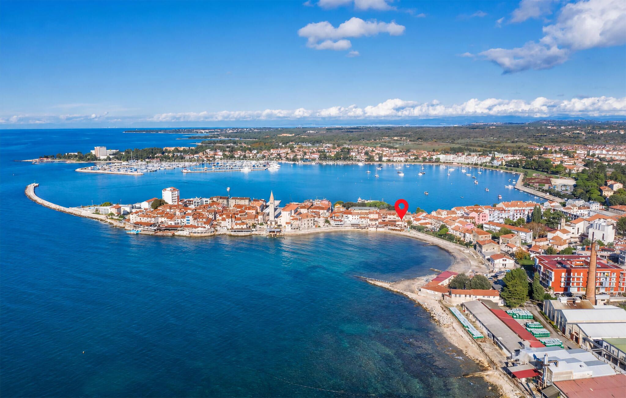 Un pueblo costero con un puerto deportivo, edificios a lo largo del muelle y un cielo azul despejado.