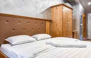 A bedroom with a large bed, wooden wardrobe, and a concrete wall. - Beach front apartment in Umag with house sea view (Umag)
