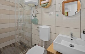 A modern bathroom with a glass shower enclosure, a white toilet, a sink with a mirror above it, and a towel rack with folded towels. - Amazing home in Rovinj with WiFi (Rovinj)