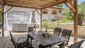 An outdoor patio with a table and chairs, a hot tub, and a pergola with a white canopy. - Amazing home in Rovinj with WiFi (Rovinj)