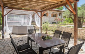 Eine Terrasss mit Tisch und Stühlen, einem Whirlpool und einem Pavillon mit weißem Baldachin.