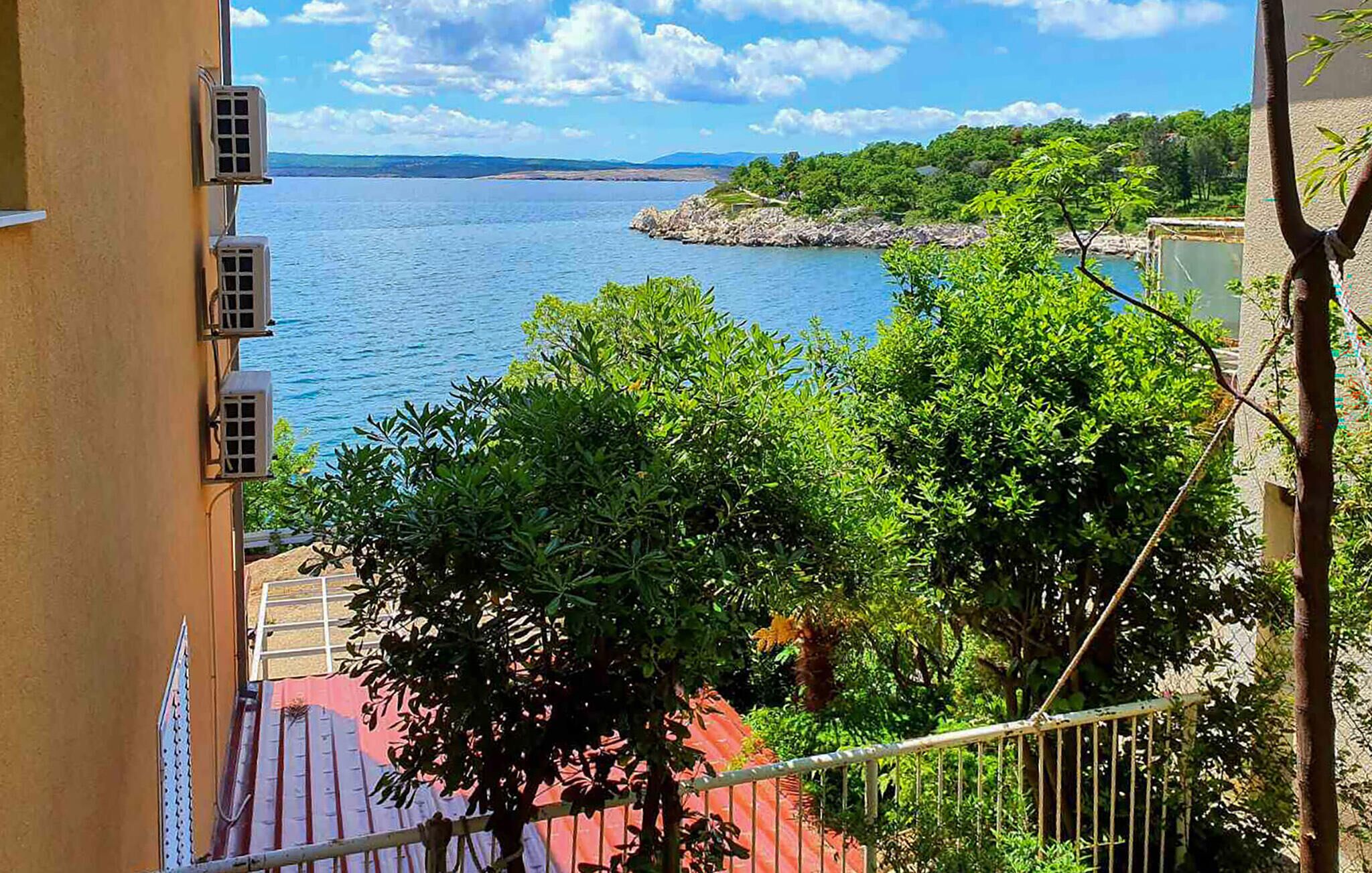 A balcony with a view of a calm sea and a distant coastline.