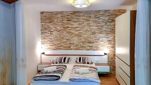 Ein Schlafzimmer mit Steinwand, einem Bett mit gestreifter Bettwäsche und einem Nachttisch.
