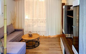 Un salon avec un canapé, une table basse ronde et un meuble pour la télévision.