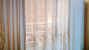 Ein Zimmer mit Blick, durchscheinende Vorhänge, ein Chandelier und eine Wand mit Muster.