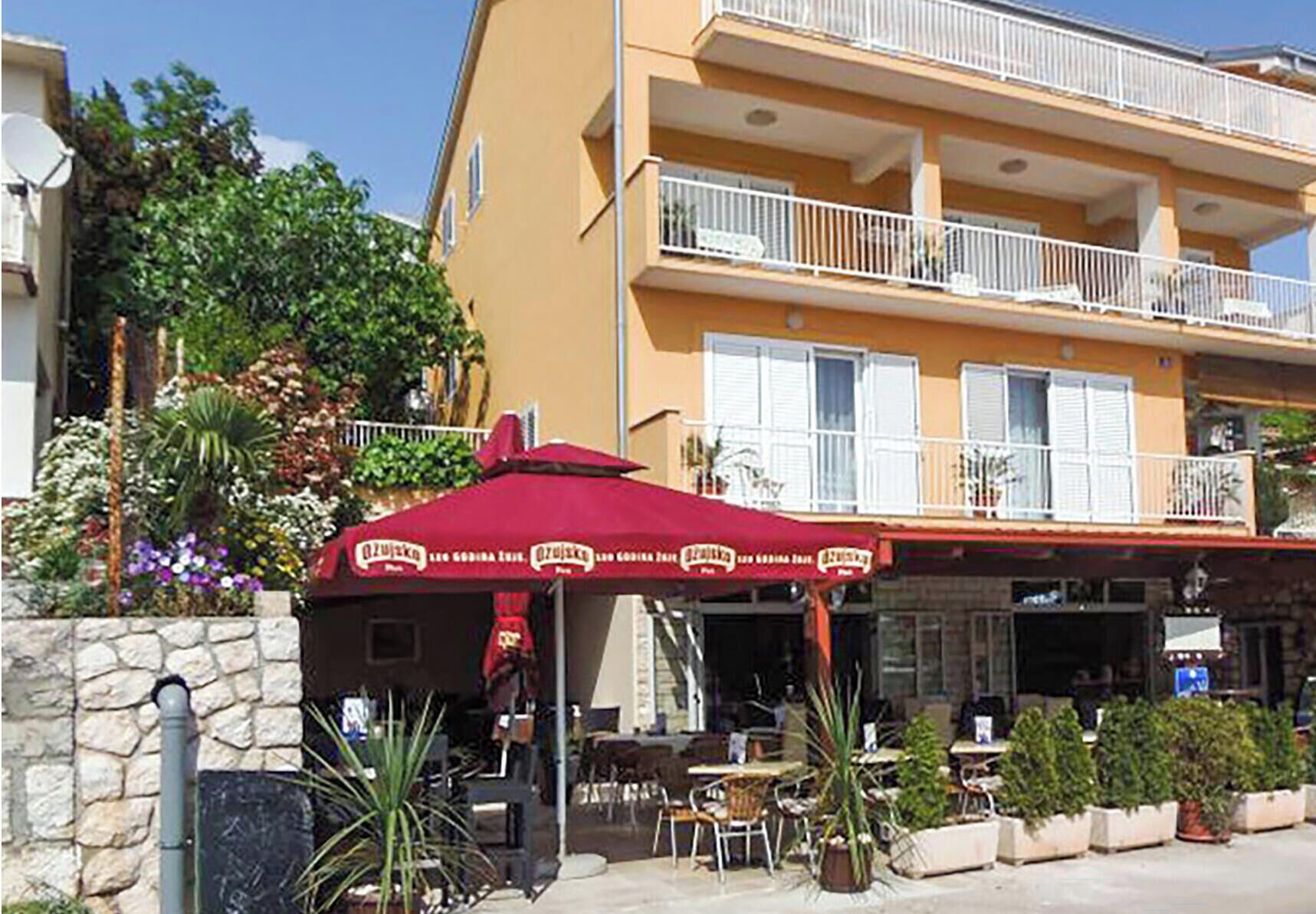 A building with a balcony, outdoor seating, and a red awning.