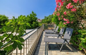 An outdoor seating area with metal railings and benches, surrounded by lush greenery and flowering plants. - Beautiful apartment in Crikvenica with WiFi (Crikvenica)