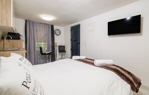 A hotel room with a bed, a television, a clock, a desk with a chair, and a window with curtains. - Beautiful apartment in Crikvenica with WiFi (Crikvenica)