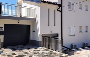 A two-story building with a tiled patio, a garage door, and a small balcony with a metal railing. - Beautiful apartment in Crikvenica with WiFi (Crikvenica)