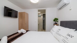 A modern hotel room with a bed, a TV, a wardrobe, and a small plant. - Beautiful apartment in Crikvenica with WiFi (Crikvenica)