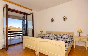 A bedroom with a bed, two bedside tables, a nightstand, a sliding glass door to a balcony, and two framed pictures on the wall. - Cozy apartment in Crikvenica with house sea view (Crikvenica)