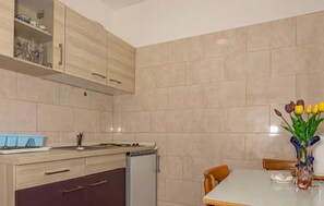 Eine Küche mit Esstisch, Stühlen, einem Kühlschrank und Schränken.