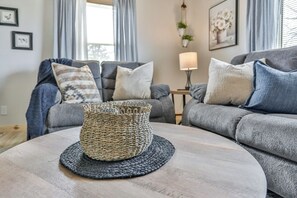 A living room with a round coffee table, two grey sofas, and a woven basket on the table. - Country Corner Inn - 3BR Stay for Professionals (Wausau)