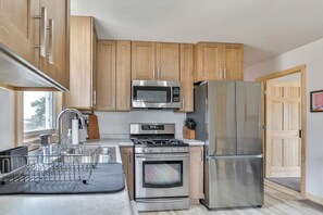 A modern kitchen with stainless steel appliances, wooden cabinets, and a black countertop. - Country Corner Inn - 3BR Stay for Professionals (Wausau)