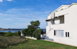 A modern two-story building with a white exterior, a visible staircase, and a view of the sea. - Awesome apartment in Povljana with WiFi (Povljana)