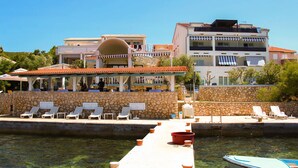 Ein Strandhotel mit Poolbereich, Liegestühlen und einer Bootsanlegestelle.