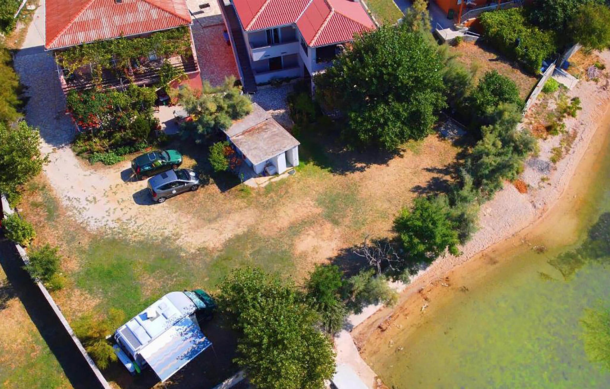 Vue aérienne d’un quartier résidentiel avec une maison, un petit bâtiment et une voiture garée.