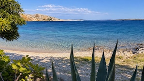 A coastal landscape with clear blue water, pebbly beach, and green vegetation. - Stunning apartment in Smokvica (Smokvica)