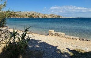 Eine Küstenlandschaft mit klarem Wasser, felsigem Gelände und spärlicher Vegetation.