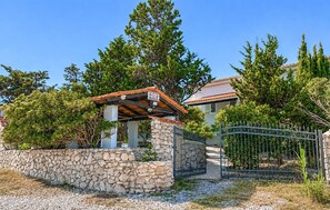 A stone wall, a metal gate, and a building with a tiled roof. - Nice apartment in Smokvica with WiFi (Smokvica)