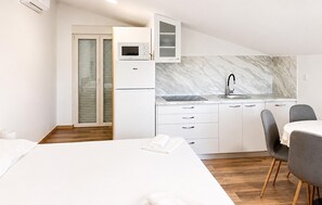 Eine moderne Küche mit Mikrowelle, Backofen und Spüle. Ein Essbereich mit Tisch und Stühlen ist ebenfalls vorhanden.