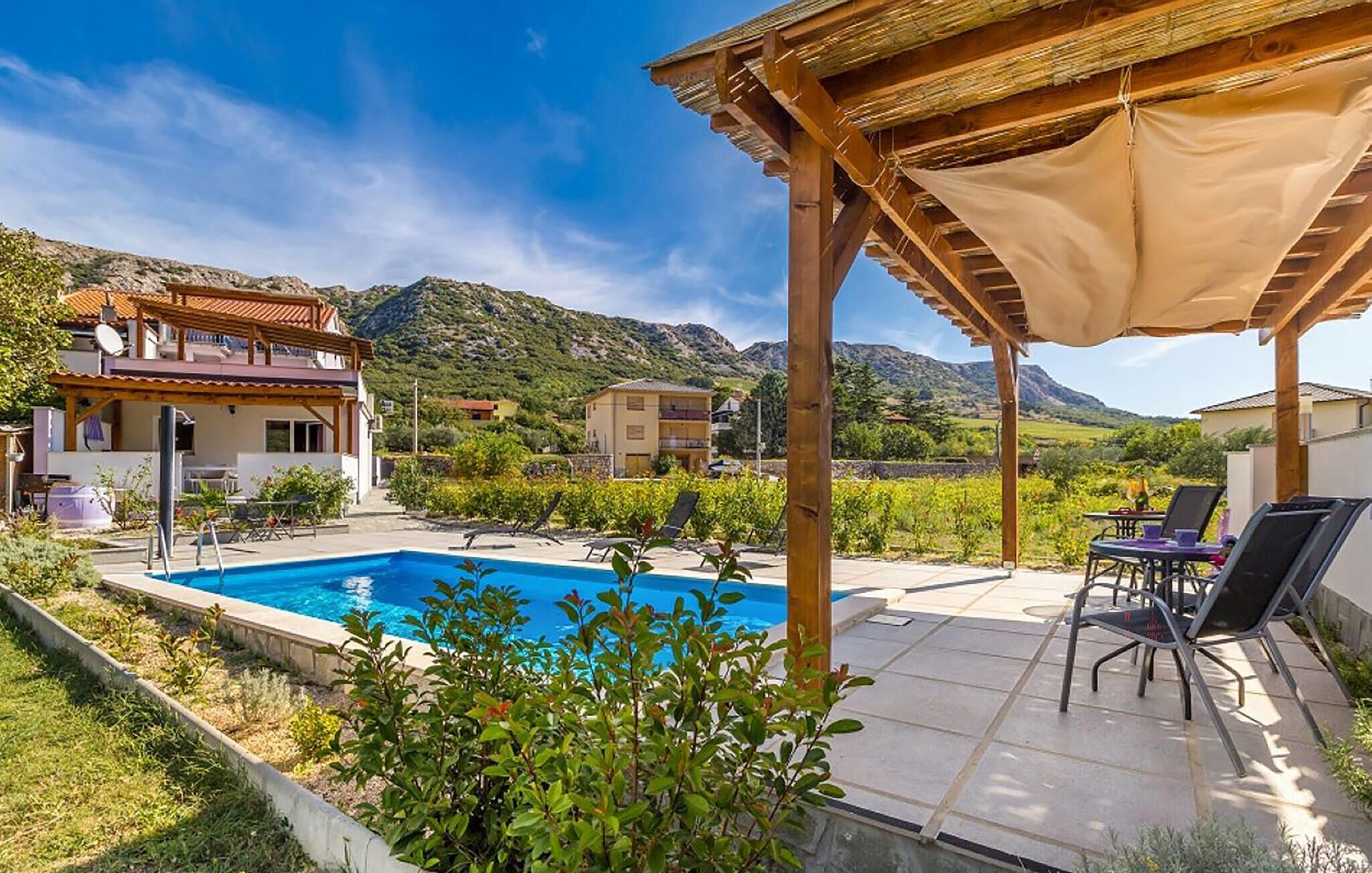 Un espace piscine agrémenté d’une pergola, de chaises longues et offrant une vue sur le paysage environnant.