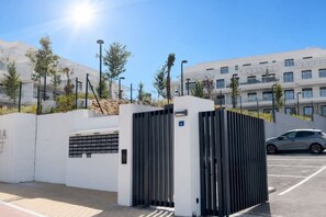 A gated entrance with a modern design, a parking area, and a building in the background. - Luxury new apartment in La Cala de Mijas (Las Lagunas de Mijas)