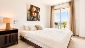 Un dormitorio moderno con una cama grande, una mesita de noche, una lámpara y un cuadro en la pared.