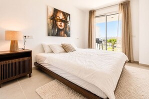 A modern bedroom with a large bed, a bedside table, a lamp, and a painting on the wall. - Luxury new apartment in La Cala de Mijas (Las Lagunas de Mijas)