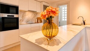 Una cocina moderna con encimera de mármol, horno empotrado y un florero con flores en la isla.