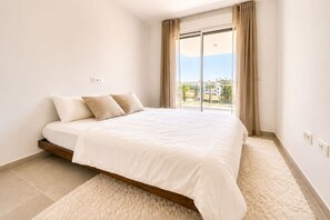 A bedroom with a bed, a window with curtains, and a view of the outside. - Luxury new apartment in La Cala de Mijas (Las Lagunas de Mijas)