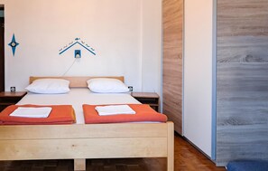 Ein Doppelbett mit zwei Kissen, ein Nachttisch und eine Wandleuchte.