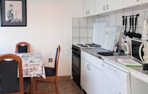 Eine kompakte Küche mit Essbereich, inklusive Tisch und Stühlen, Kühlschrank, Herd und Mikrowelle.