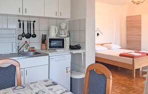 Eine kleine Küchenzeile mit Mikrowelle, Kaffeemaschine und Geschirr.
