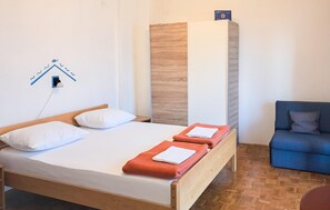 A single bed with white bedding and two orange towels, a blue chair, and a wooden wardrobe with a vertical wooden panel. - Stunning apartment in Novi Vinodolski with WiFi (Novi Vinodolski)