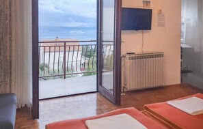 Ein Zimmer mit Balkon, einem an der Wand befestigten Fernseher und einer Heizung.