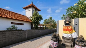 A courtyard with a tiled roof building, a wall with a statue, and a clear sky. - Collection O near Pantai Nusadua formerl (Nusa Dua)