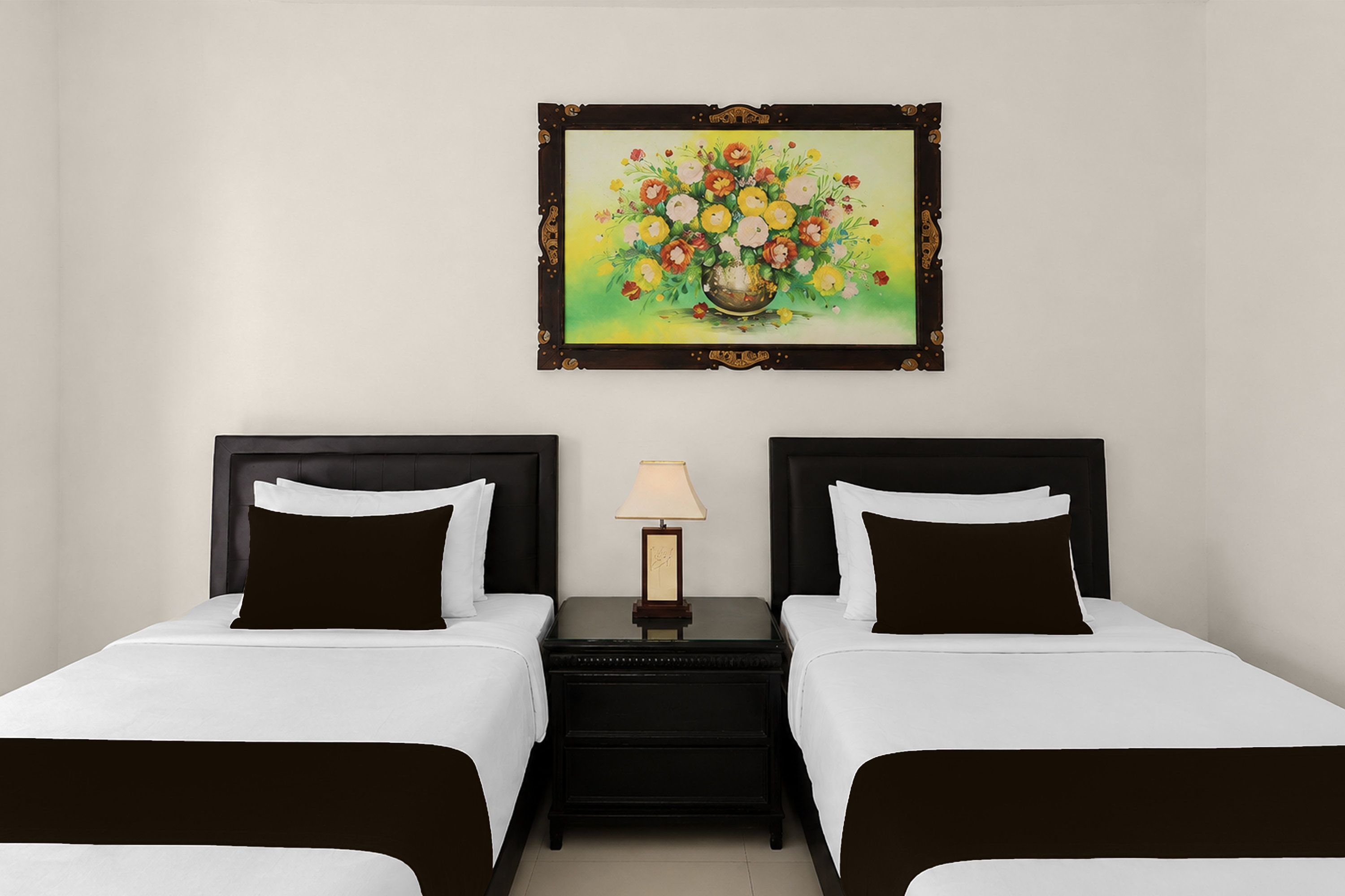 A hotel room with two beds, a nightstand with a lamp, and a framed floral painting on the wall.