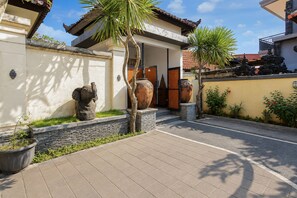 A courtyard with a traditional building, stone statues, and a tiled walkway. - Collection O near Pantai Nusadua formerl (Nusa Dua)