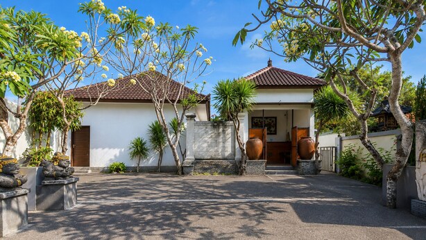 A traditional house with a tiled roof, a front porch, and a stone wall. - Collection O near Pantai Nusadua formerl (Nusa Dua)