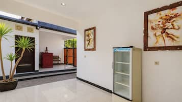 A hallway with a refrigerator, a bench, and a door leading to another room.