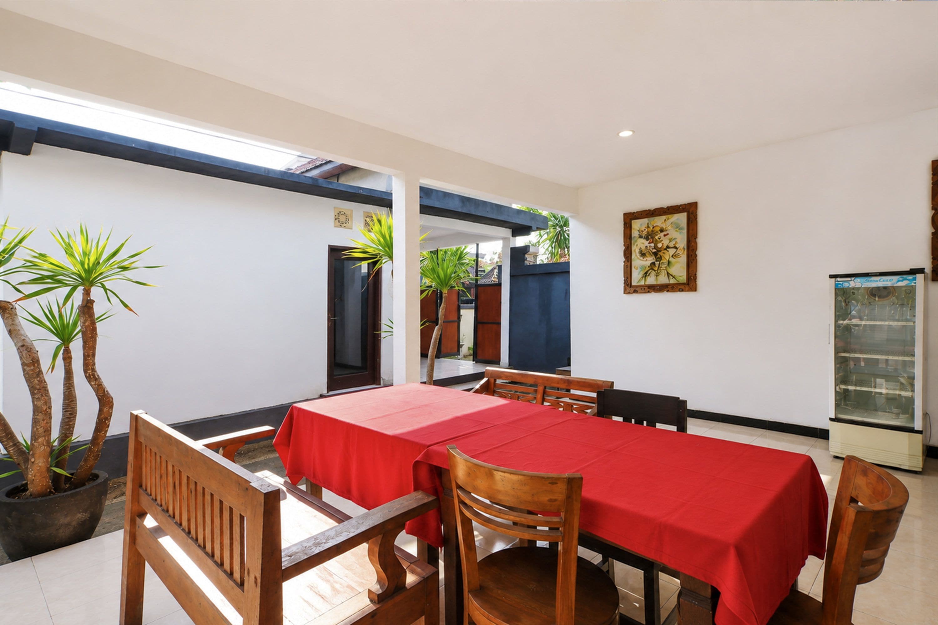 A dining area with a table set for four, surrounded by wooden chairs, with a red tablecloth.